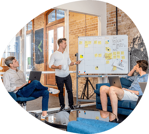 Consultants holding a meeting around a whiteboard